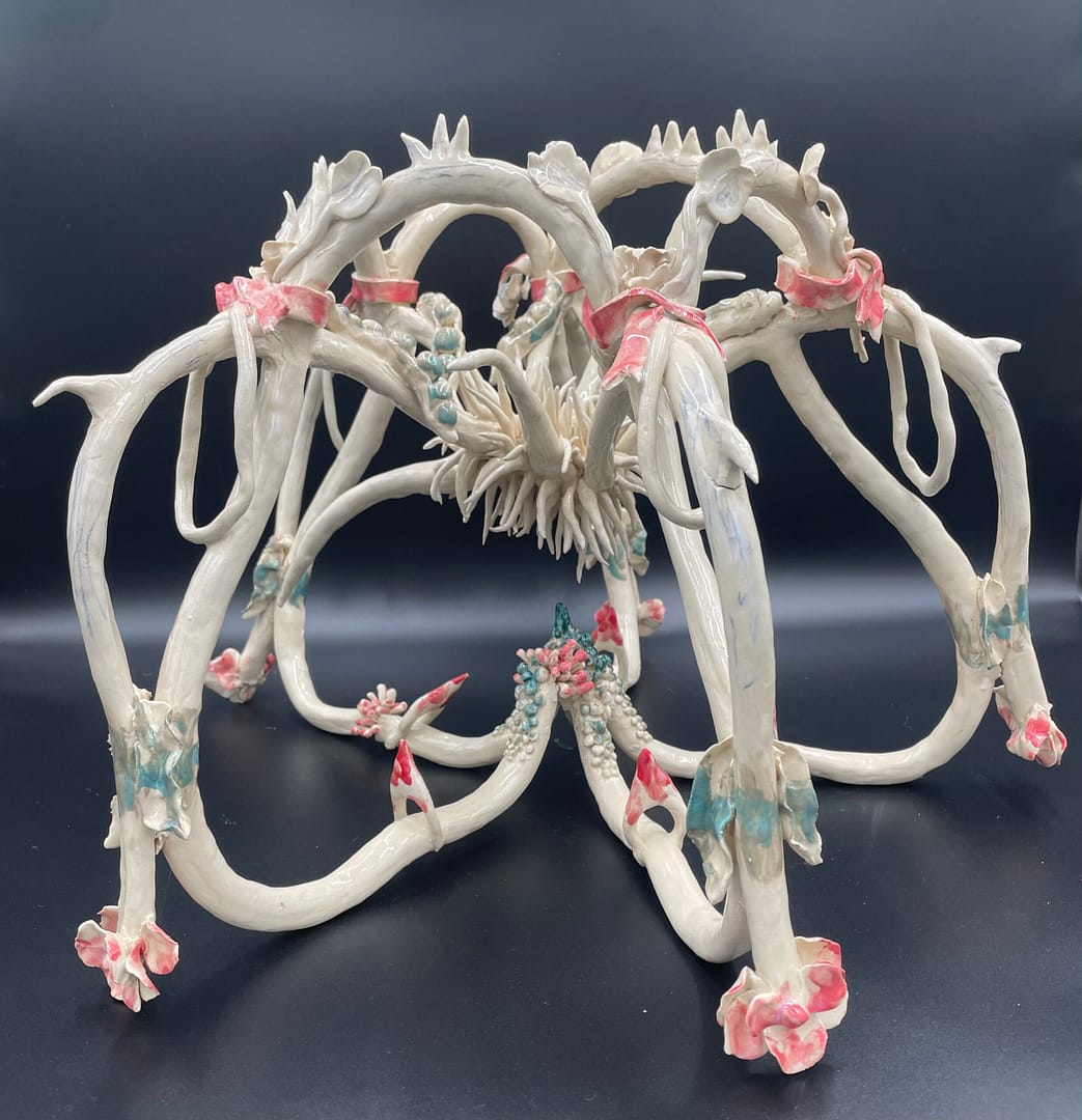 Clara Lundgrens sculpture consists of several interconnected arcs of varying sizes, crafted from ceramic. These arcs form an organic, flowing shape that extends upward and outward from a central base.